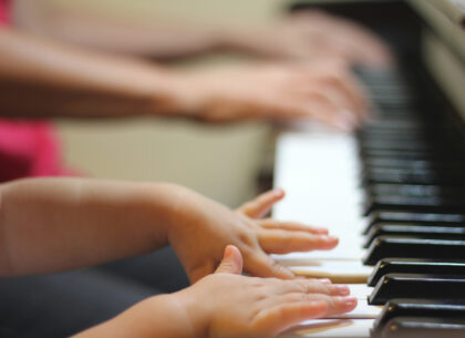 Lapsen ja aikuisen kädet soittamassa pianoa.
