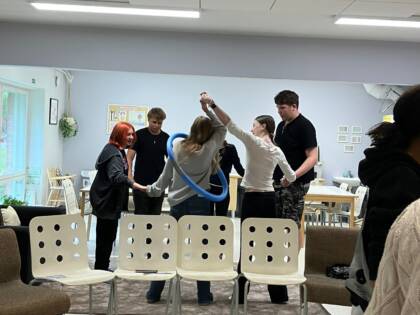 Nuoria ihmisiä istumassa tuoleilla ringissä ja yhdellä heistä kirja sylissään.