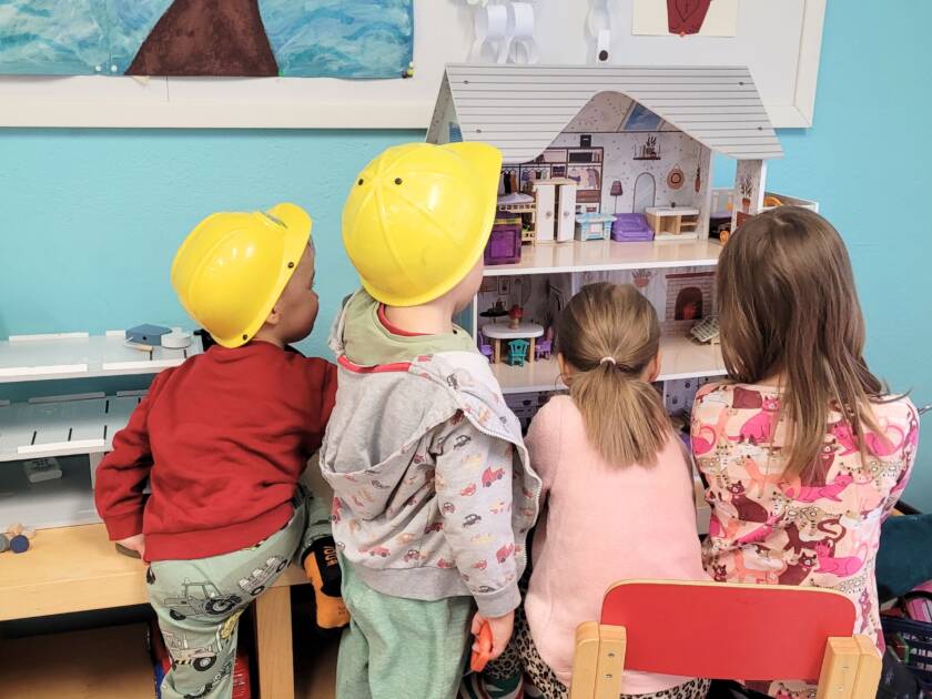 Lapsia selin leikkimässä nukkekodilla.